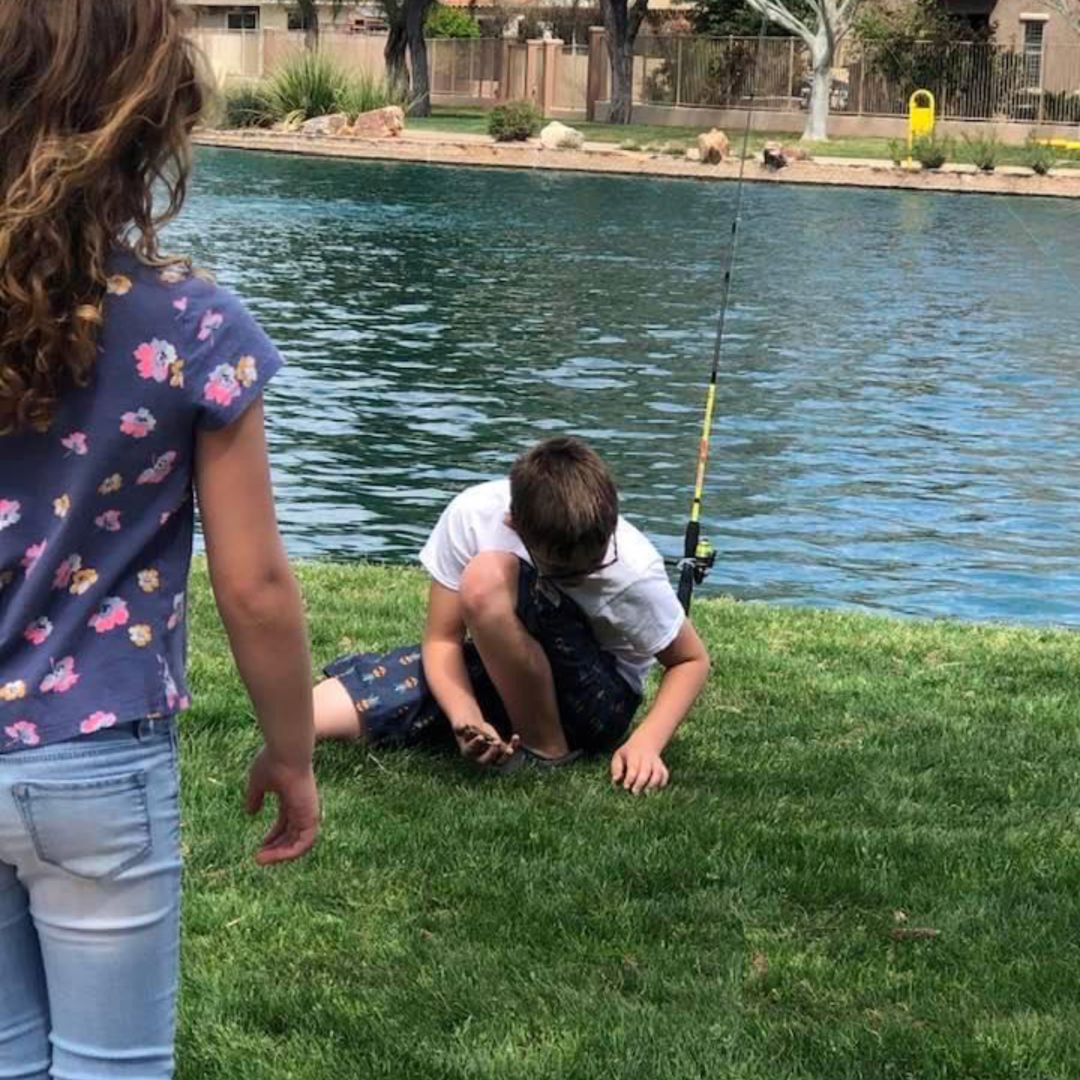 children playing at a lake, one fishing