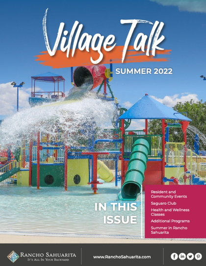 Cover of "Village Talk" Summer 2022 magazine, featuring a colorful water playground with slides, fountains, and a large dumping bucket. Blue sky and palm trees are in the background.