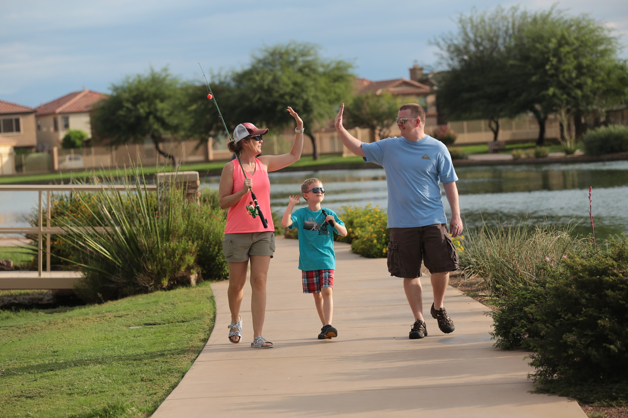 Parents and child exchanging high fives while walking with fishing poles