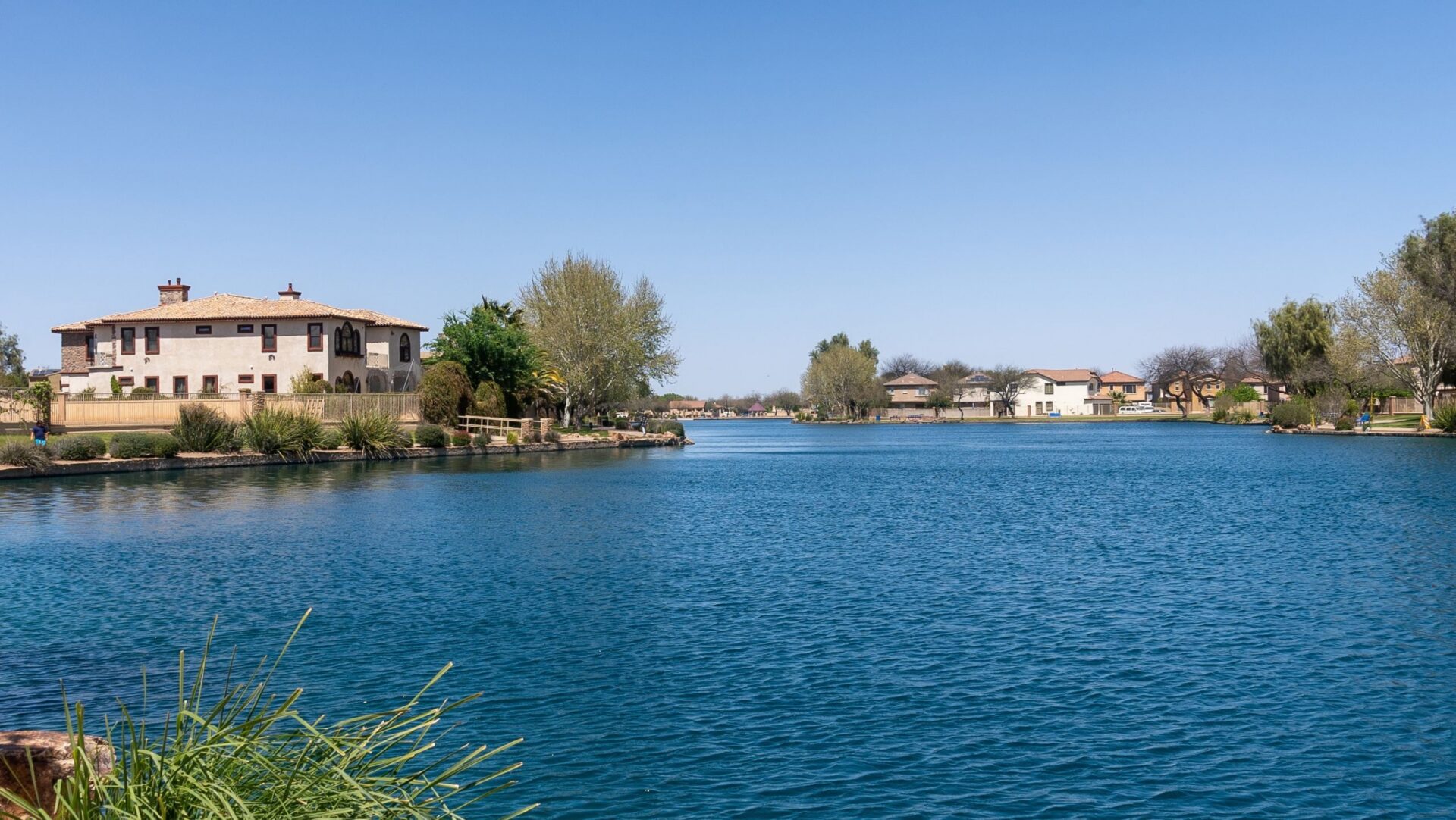 Sahuarita Lake at Rancho Sahuarita, surrounded by mature trees, walking paths and homes beneath a clear Arizona sky.