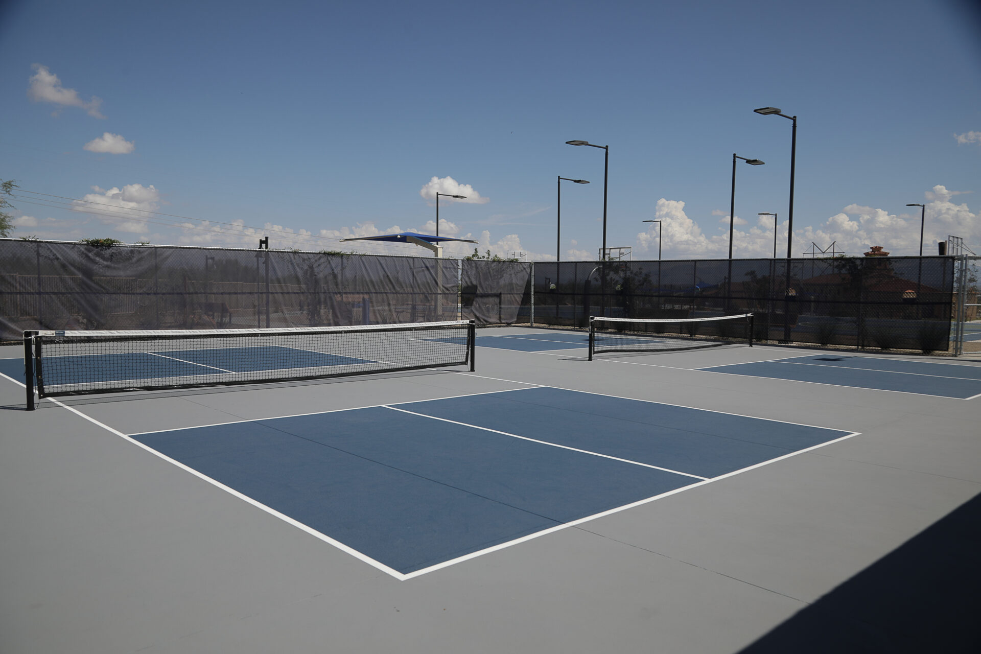 Empty outdoor pickleball courts with blue surfaces and white boundary lines.